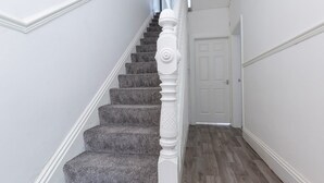 Eine Treppe mit weißer Brüstung und Teppichstufen führt zu einer weißen Tür.