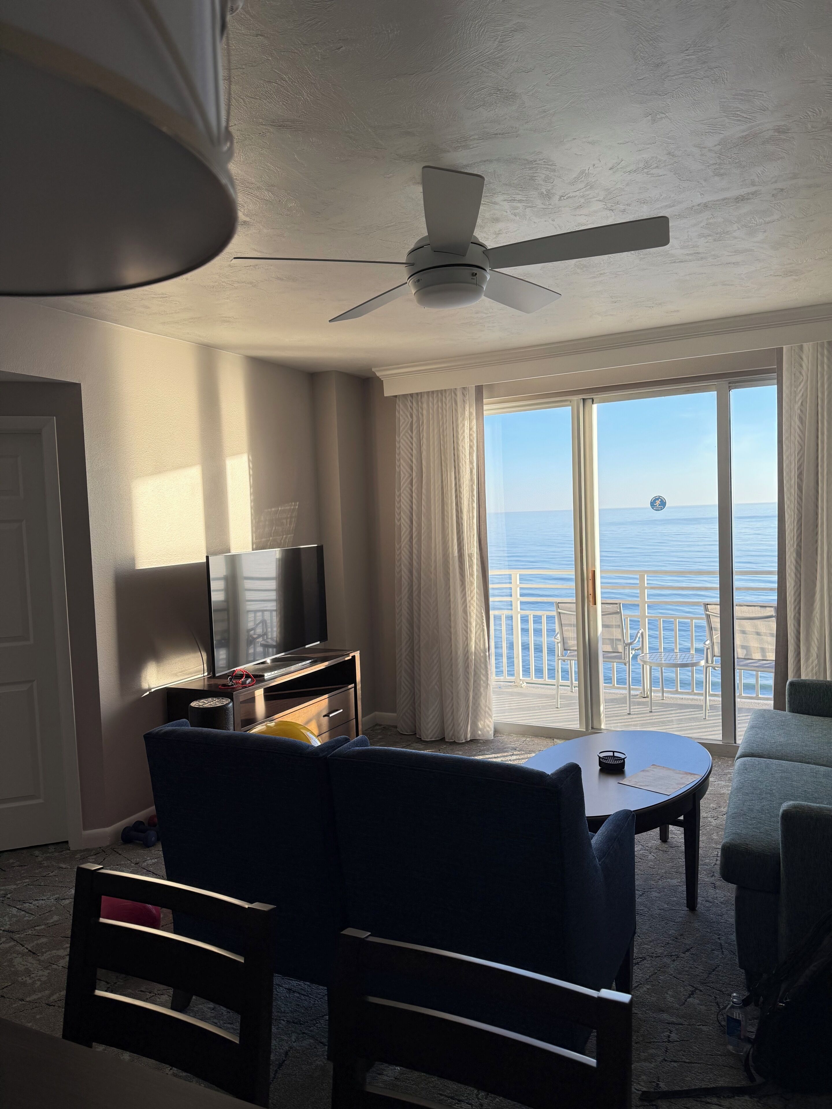 Et hotelværelse med balkon, ventilator, TV og havudsigt.