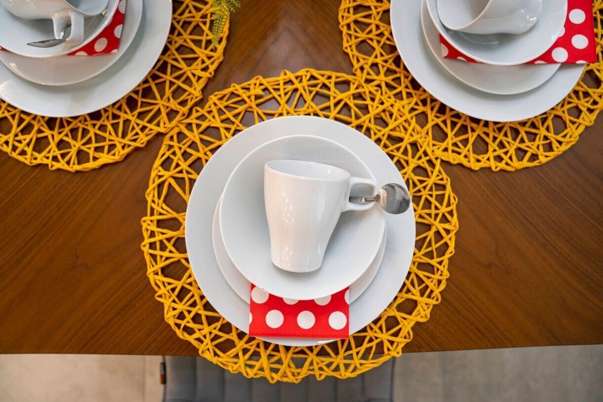 A table set with white plates, a white cup, and a red napkin with white polka dots.