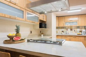 A modern kitchen with wooden cabinets, a central island with a built-in stove, and a microwave above it. - Huge 4BR super located (Ciudad de México)