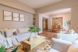 A modern living room with a sofa, coffee table, and a dining area with chairs and a table. - Huge 4BR super located (Ciudad de México)