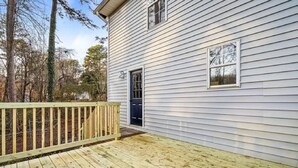 A single-story house with a wooden deck and a black door.