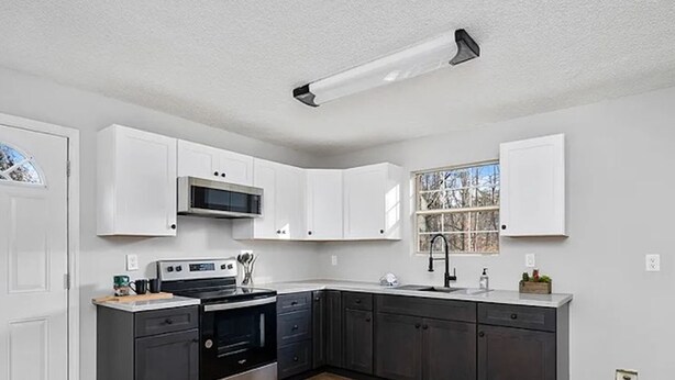 A modern kitchen with white cabinets, a stainless steel range, and a black oven.