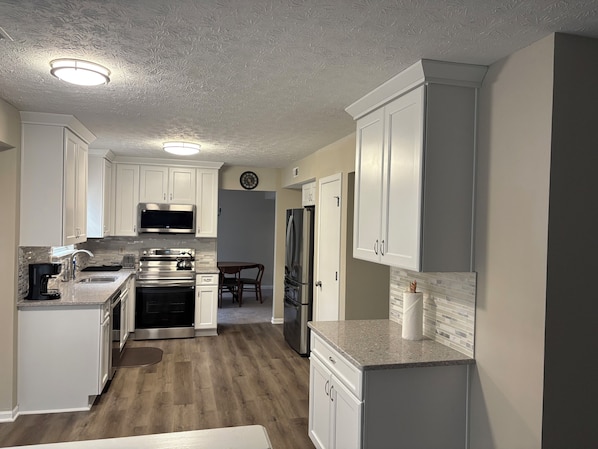 Una cocina moderna con armarios blancos, microondas, estufa y refrigerador.