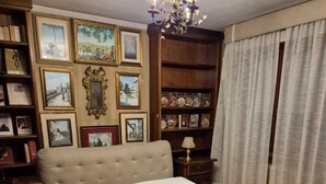 A bedroom with a large bed, a chandelier, a bookshelf with framed pictures, and a patterned rug. - 100 meters from the historic center of Lucca with free parking. (Lucca)
