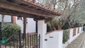 A white building with a brick chimney, a metal gate, and a pergola. - 100 meters from the historic center of Lucca with free parking. (Lucca)