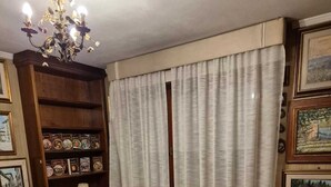 A bedroom with a large bed, a chandelier, a bookshelf, and a small table. - 100 meters from the historic center of Lucca with free parking. (Lucca)