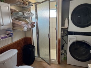 Een wasserette met een wasmachine, een droger en planken met opgevouwen handdoeken.