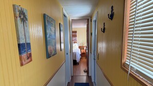 Käytävä, jossa on puulattiat, keltaiset seinät ja taideteoksia.