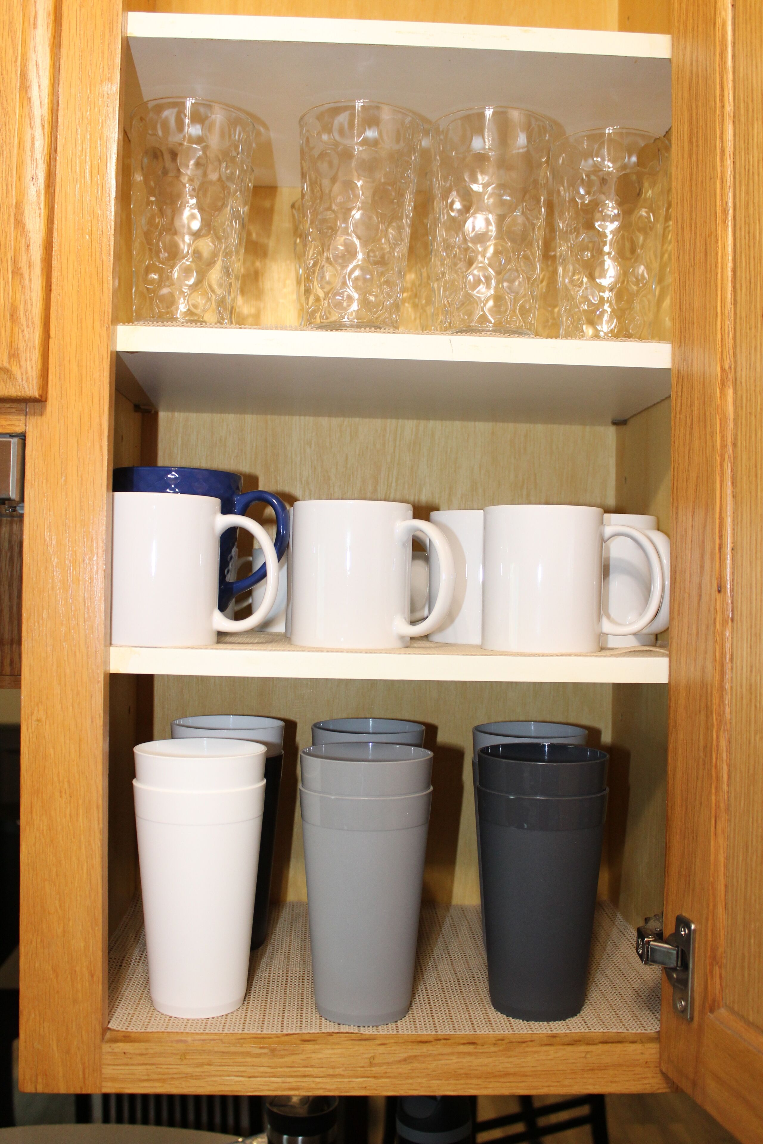 A wooden cabinet with shelves holding various mugs and cups.