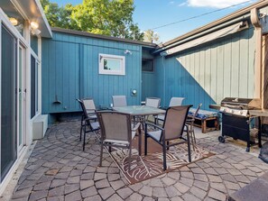 A patio with a table and chairs, a grill, and a blue wall. - Bright & Cozy Home - Sunroom, Games & Foosball in La Vista, NE (La Vista)
