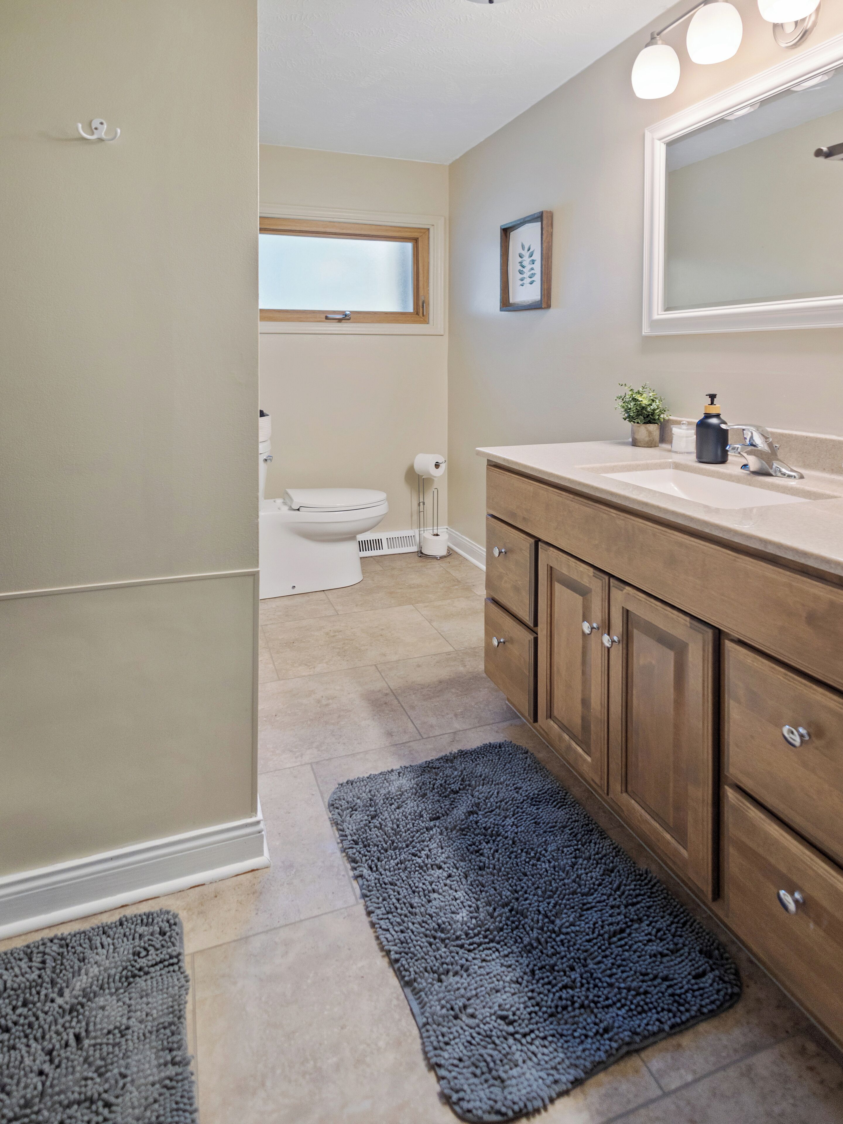 A bathroom with a toilet, sink, and mirror.