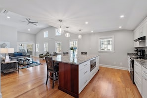 A spacious kitchen with a large island, wooden flooring, and white cabinetry.