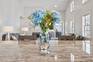 A marble countertop with a vase of flowers and a candle labeled 'Rock Port Candle Company.'