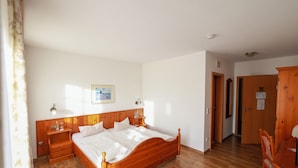 Een slaapkamer met een houten bed, nachtkastjes, een kledingkast van hout en een deur naar een andere kamer.