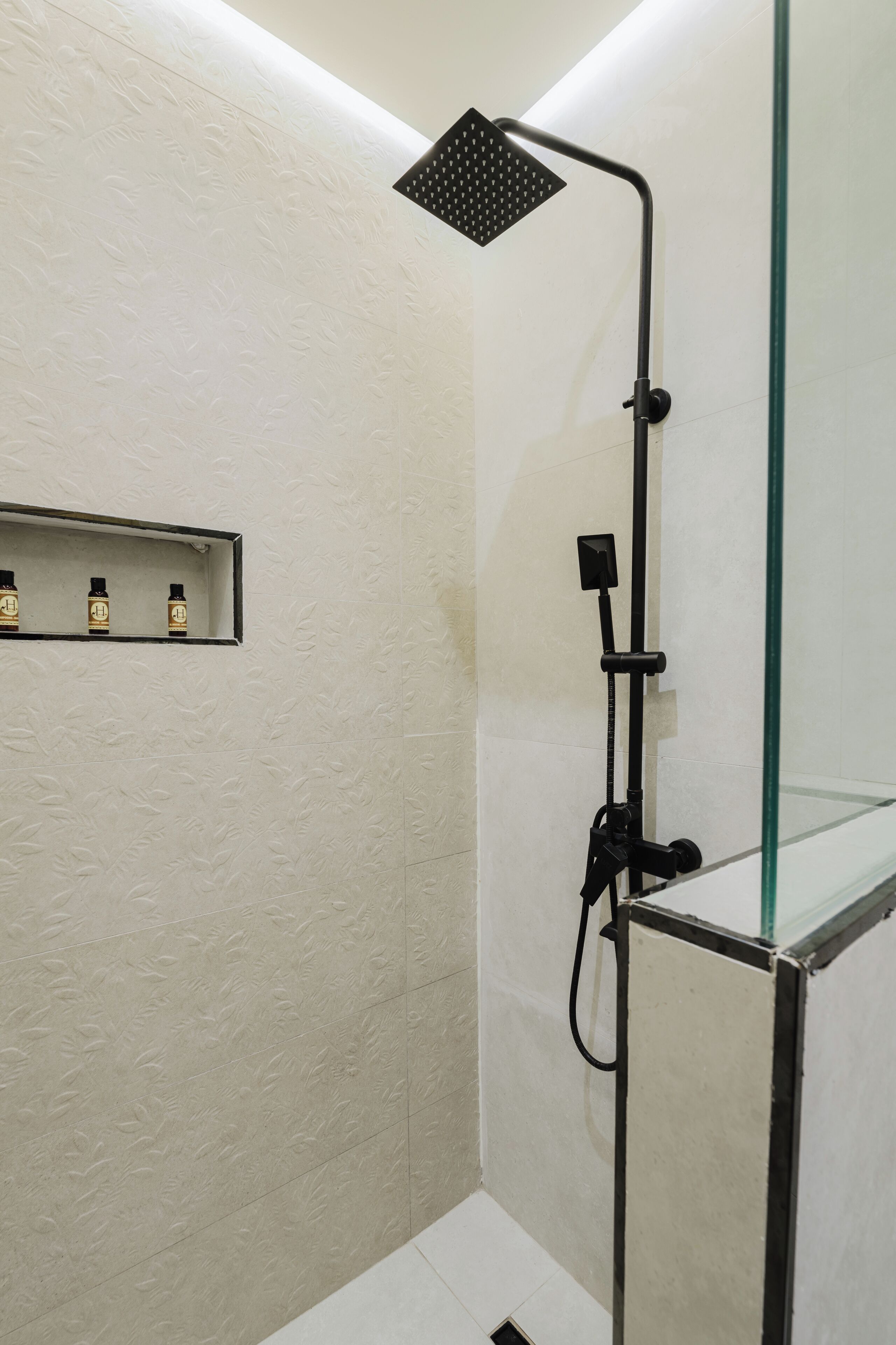 Een moderne douche met een glazen cabine, een handdouche en een bedieningspaneel.