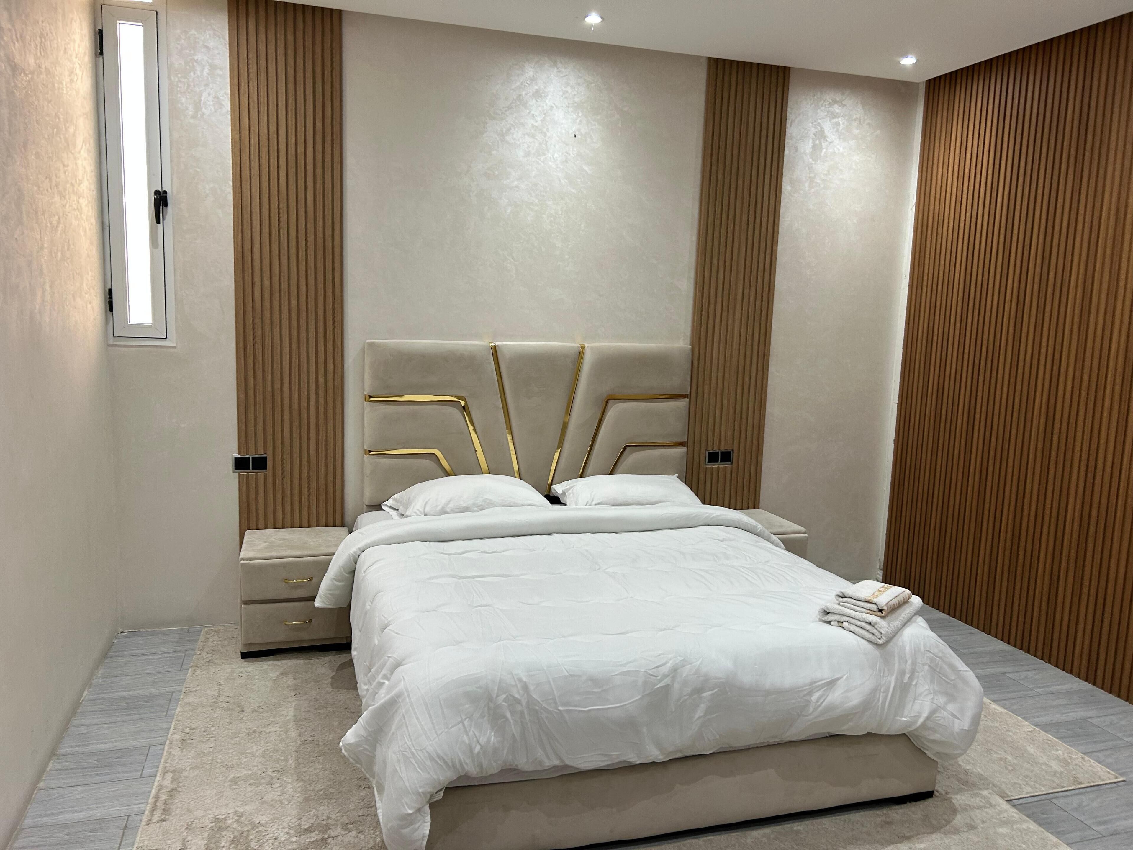 A modern bedroom with a large bed, a bedside table, and a built-in wardrobe.
