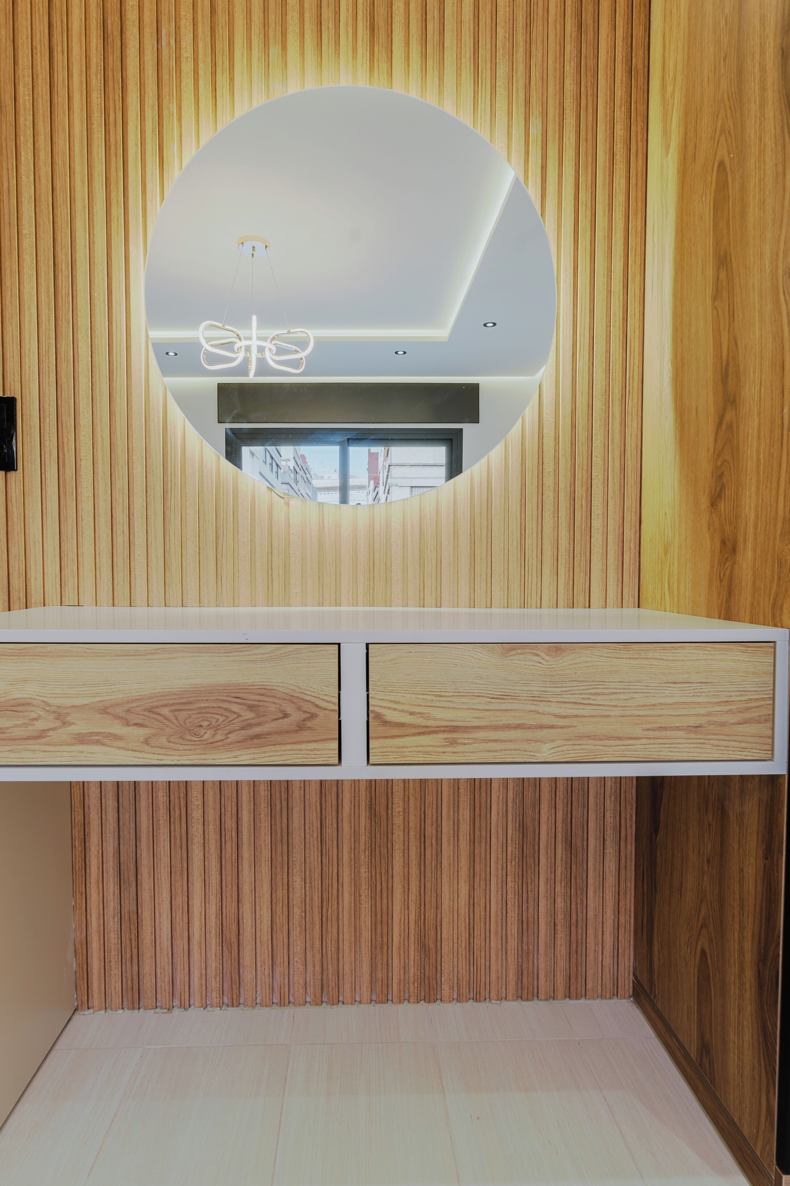A room with a wooden panel wall, a circular ceiling light, and a white cabinet with drawers.