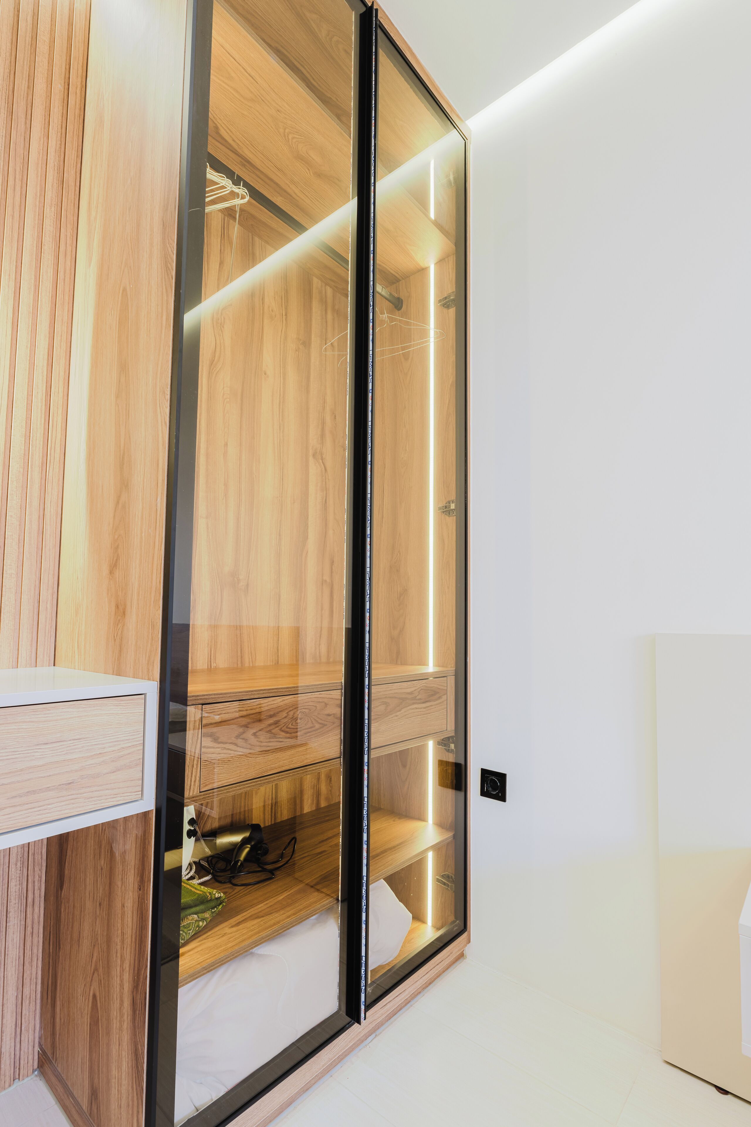 A modern bathroom with a wooden vanity, a glass shower enclosure, and a white sink.