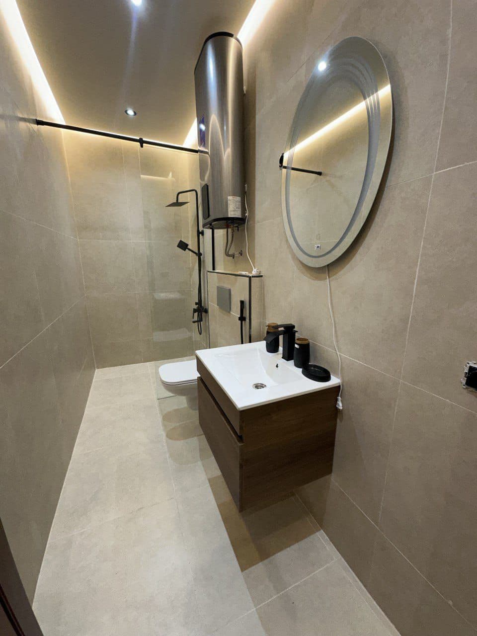 Une salle de bain moderne équipée d’un WC, d’un lavabo, d’un miroir et d’une douche.