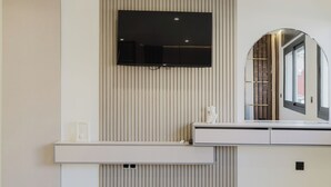 A modern bedroom with a TV mounted on the wall, a bedside table, and a large mirror. - el boujdaini (Tangier)
