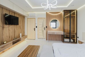 A modern bedroom with a TV mounted on a wooden panel wall, a bedside table, a bed with white bedding, and a walk-in closet with a mirror. - el boujdaini (Tangier)