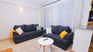 A living room with two dark sofas, a white coffee table, and a small rug. - Serene Homes Membley- Executive 1-Bedroom in Ruiru- Secure & Affordable (Ruiru)