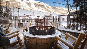 A wooden outdoor seating area with a fire pit, snow-covered chairs, and a view of a snowy mountain landscape. - Delightful 2-bedroom suite at the Marriott Mountainside Resort in Park City. (Park City)