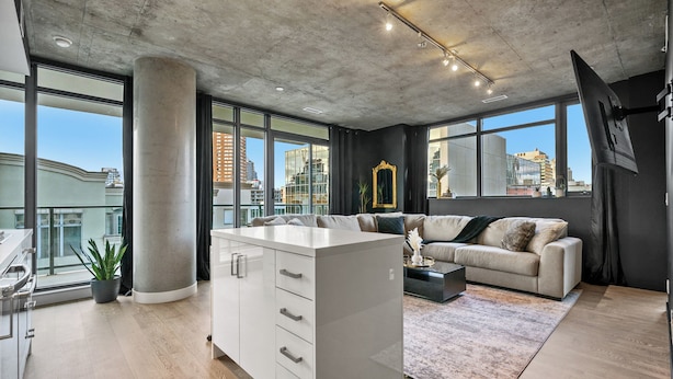 A modern living room with a large island, a sofa, and a view of the city. - Luxury 2BR/2BA Condo in Calgary Beltline | King Bed, Free Underground Parking (Calgary)