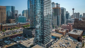 A high-rise building with a modern glass facade, surrounded by other tall buildings and a parking lot. - Luxury 2BR/2BA Condo in Calgary Beltline | King Bed, Free Underground Parking (Calgary)