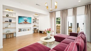 Een moderne woonkamer met een zithoek, een salontafel met een bloevas, en een groot schilderij aan de muur.