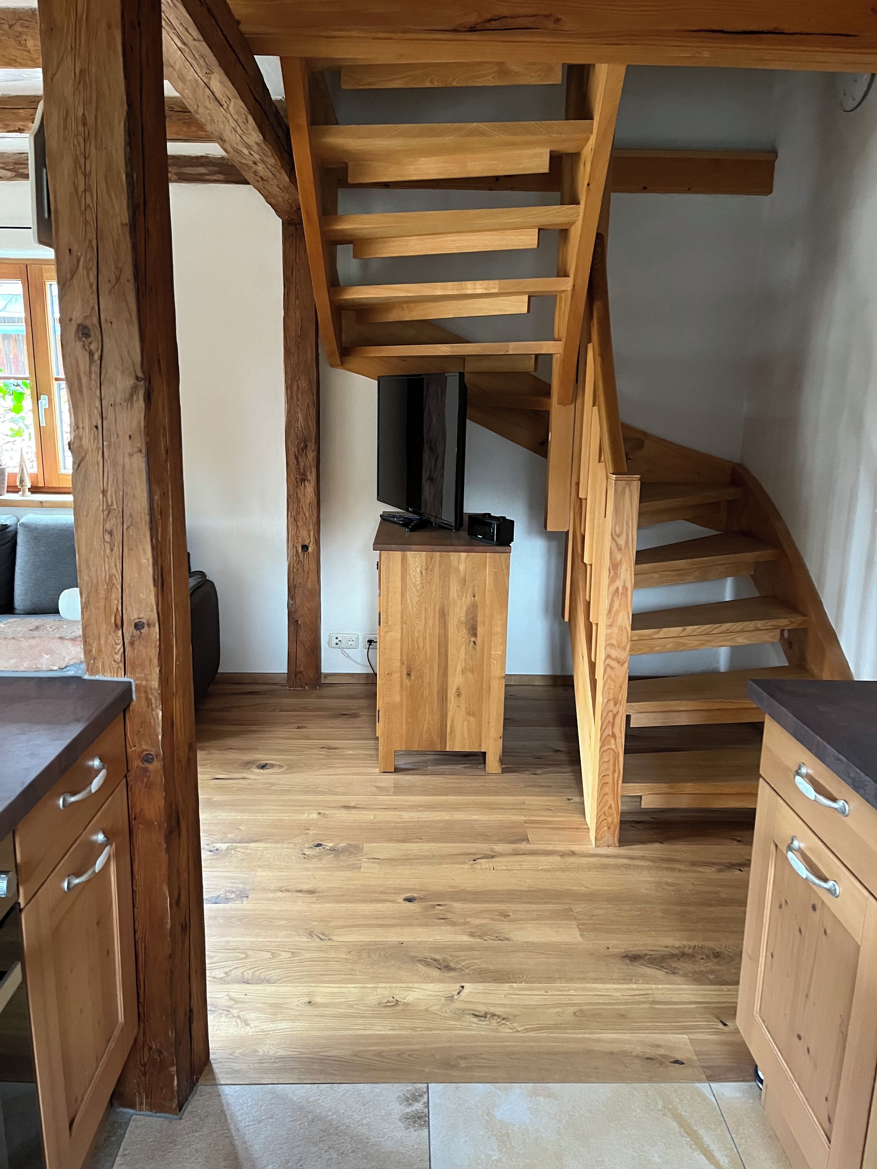 Eine Holztreppe mit flachem Dach, ein Holzschrank mit Schubladen und ein Fernseher auf einem Standfuß.
