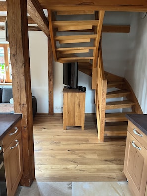 A wooden staircase with a flat roof, a wooden cabinet with drawers, and a television on a stand.