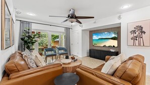 Un salon moderne avec des canapés en cuir, une table basse ronde et un ventilateur de plafond.