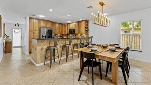 Une cuisine moderne avec des meubles en bois, un îlot central et un coin repas comprenant une table et des chaises en bois.