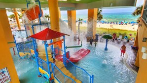 Parque aquático com piscina, toboáguas e vista para a praia.