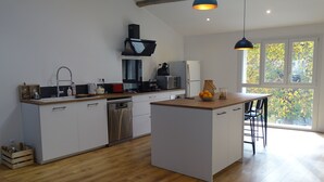 A modern kitchen with white cabinets, a wooden countertop, a built-in dishwasher, and a large island with bar stools. - Country house in the Ariege ideal for skiing, hiking, biking, snowshoeing, fishing... (Gudas)