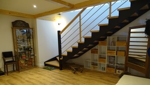 A wooden staircase with a glass enclosure on the left, a white sofa on the right, and a wooden floor. - Country house in the Ariege ideal for skiing, hiking, biking, snowshoeing, fishing... (Gudas)