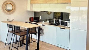 Uma cozinha moderna com ilha central, eletrodomésticos embutidos e um espelho redondo na parede.