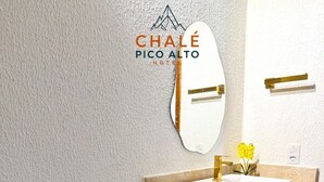 A modern bathroom with a white sink, a mirror, and a towel rack. - Chalé Pico Alto (Guaramiranga)