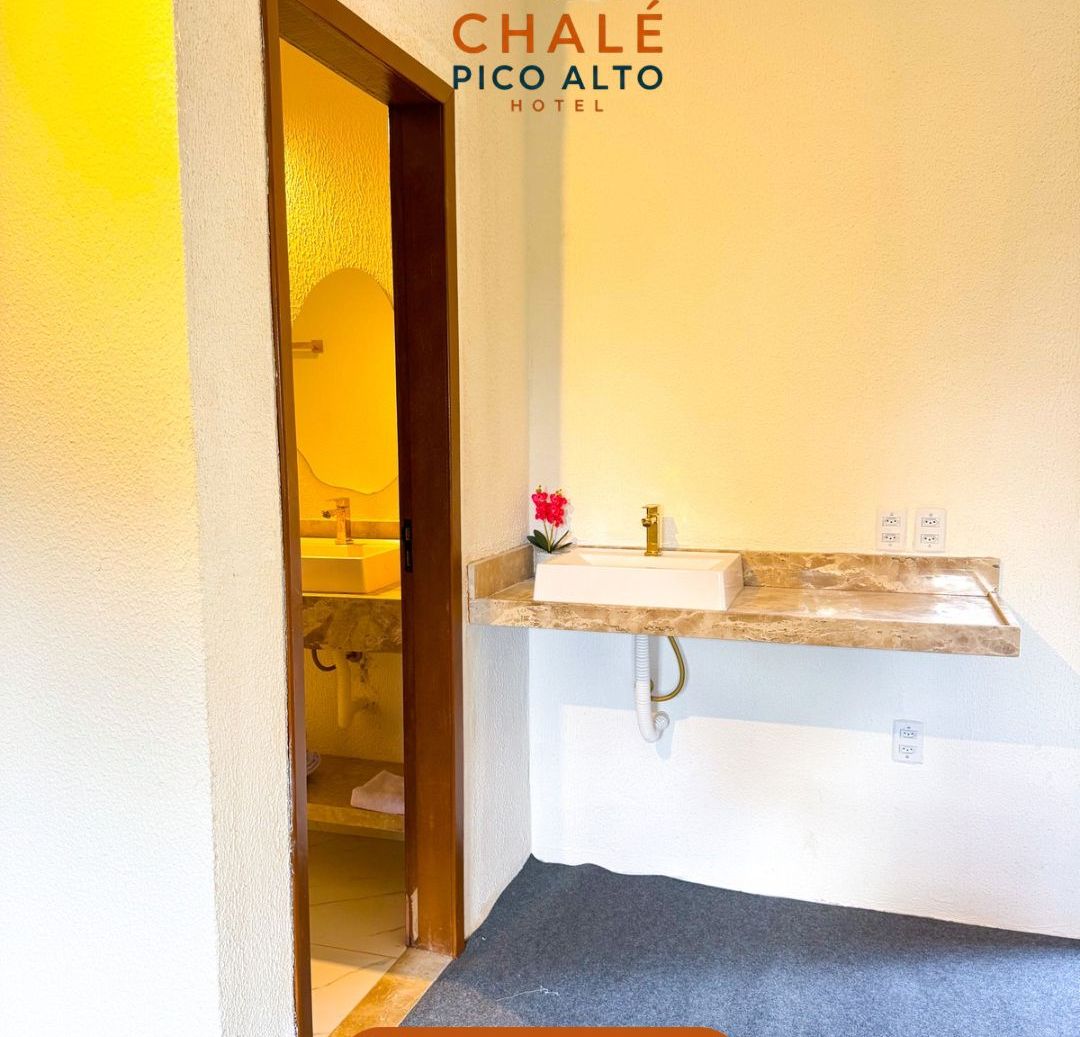 Casa de banho de hotel com lavatório, espelho e porta para outro quarto.