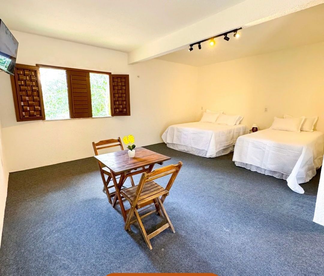 Una habitación de hotel con una mesa de comedor y dos camas.