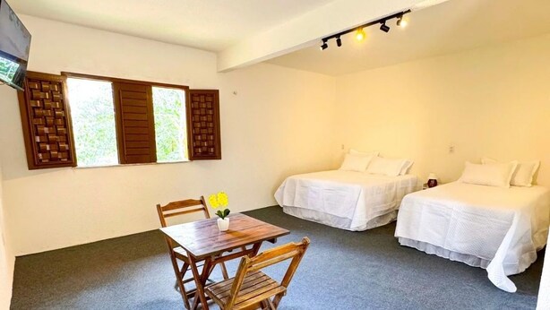 Quarto de hotel com mesa de jantar e duas camas.