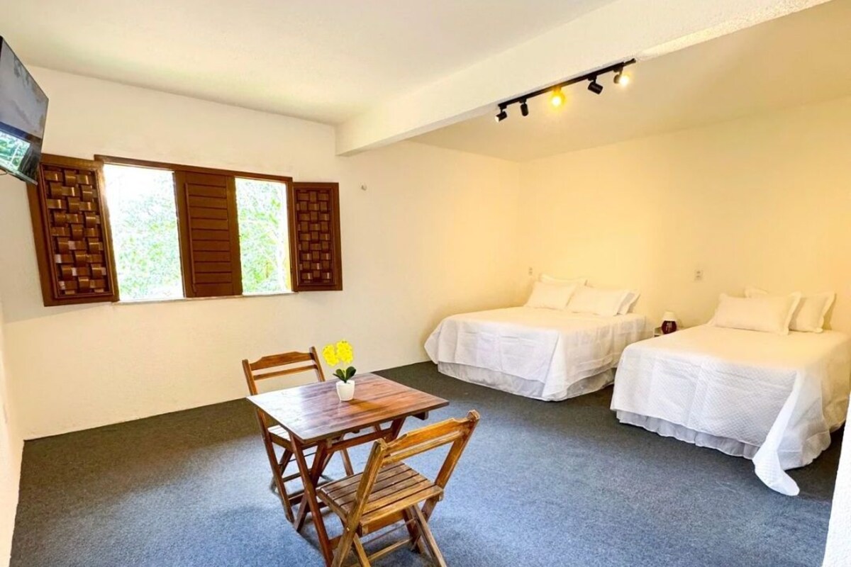 Quarto de hotel com mesa de jantar e duas camas.
