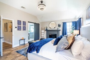 Un dormitorio con cama, chimenea, espejo y puerta que da a un balcón.