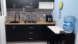 Uma cozinha compacta com pia, fogão e um dispensador de água.