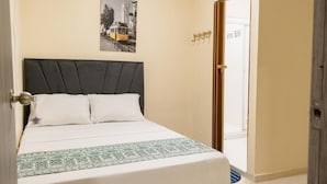A bedroom with a bed, a door, and a wall-mounted picture. - Hostal la terraza sm (Santa Marta)