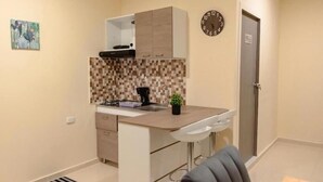 A compact kitchen with a tiled backsplash, a built-in cabinet, a small sink, and a clock on the wall. - Hostal la terraza sm (Santa Marta)