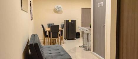 A compact hotel room with a kitchenette, a dining area, and a small seating area.