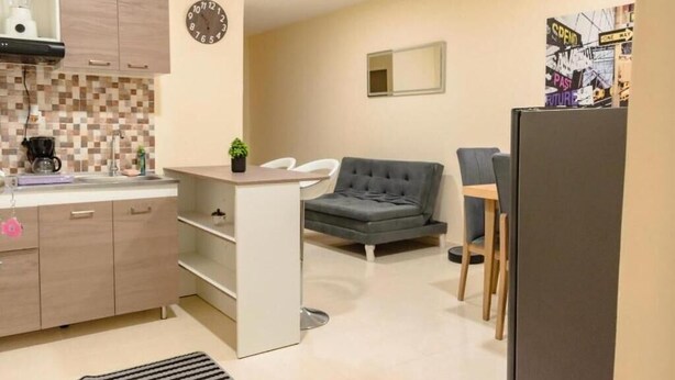 A compact kitchen with a coffee machine, a clock, and a small plant. - Hostal la terraza sm (Santa Marta)